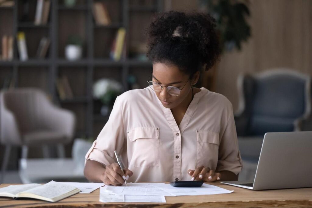 African-American woman calculating capital gain tax on real estate property.