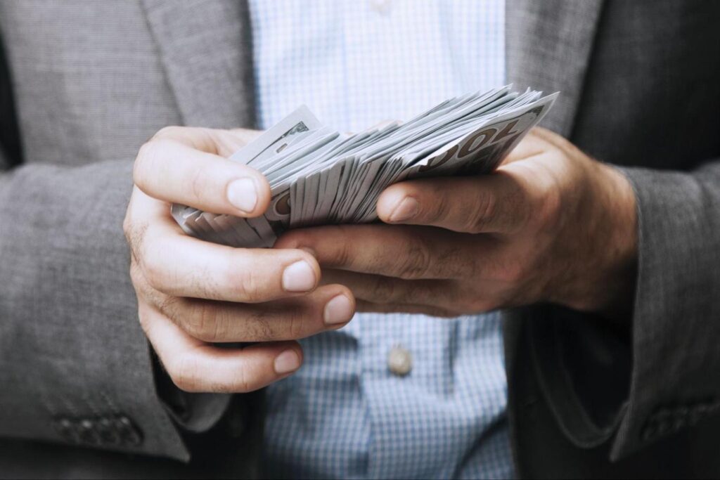 Man holding several hundred dollar bills in hand.