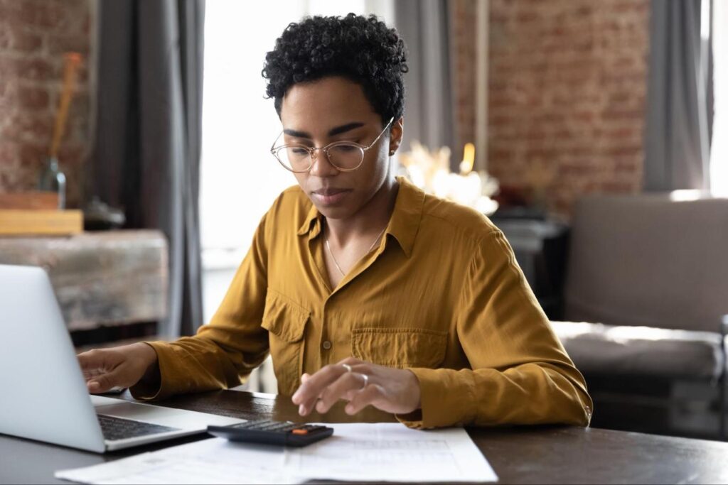 Young Black woman calculating mortgage rate lock extension fees.