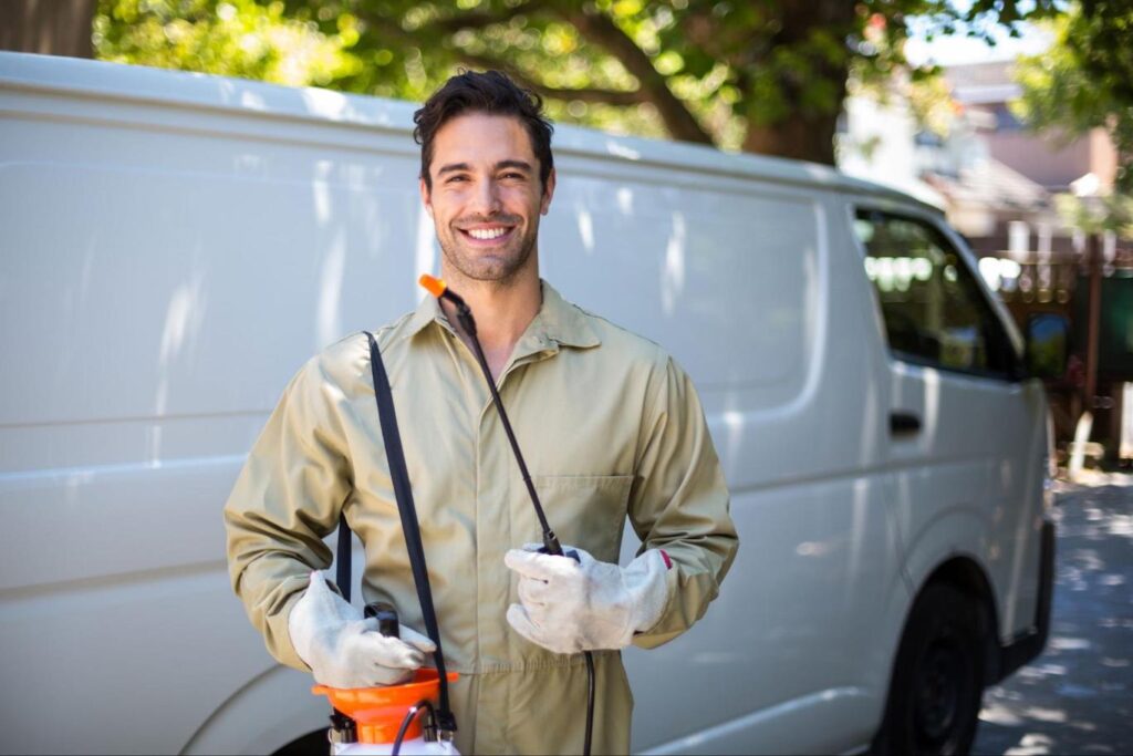 Smiling pest control technician with pesticide sprayer.
