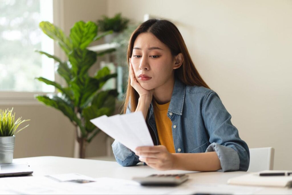 Young Asian woman stressed about finances and notice of default.