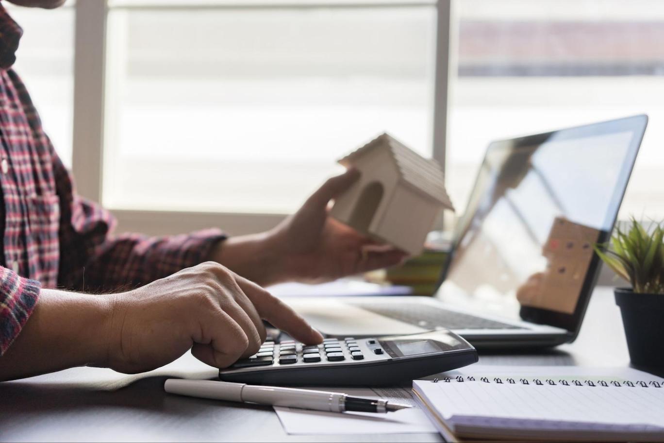 Close up of man calculating property tax with a calculator