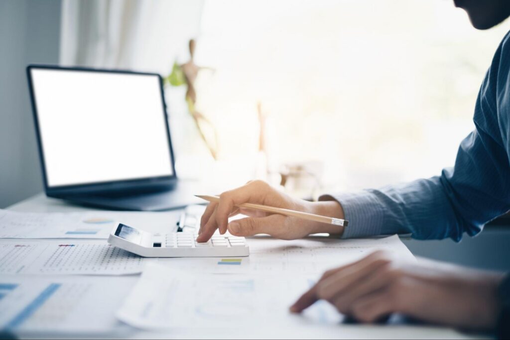 A person using a calculator on their desk with a pencil in hand.