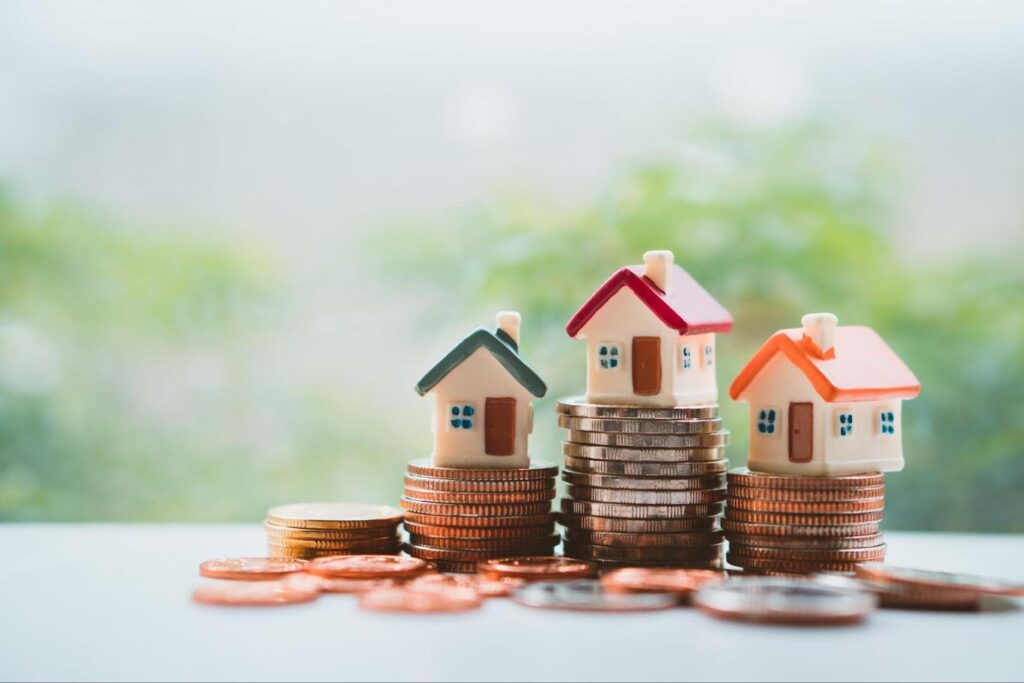 Miniature home stacked on a pile of coins.