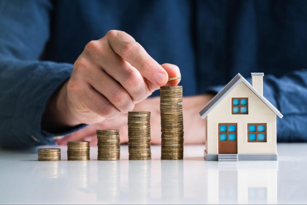 Stacks of coins next to a small model of a house