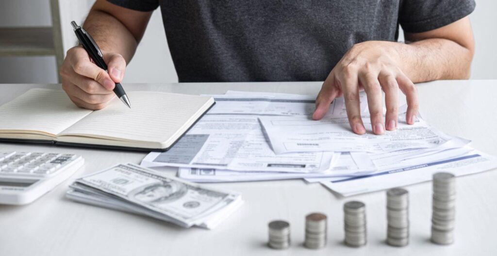 A person at their desk reviews financial documentation and bank statements.