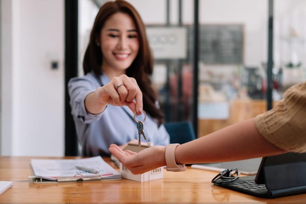 Asian woman giving keys to new owner after selling house.