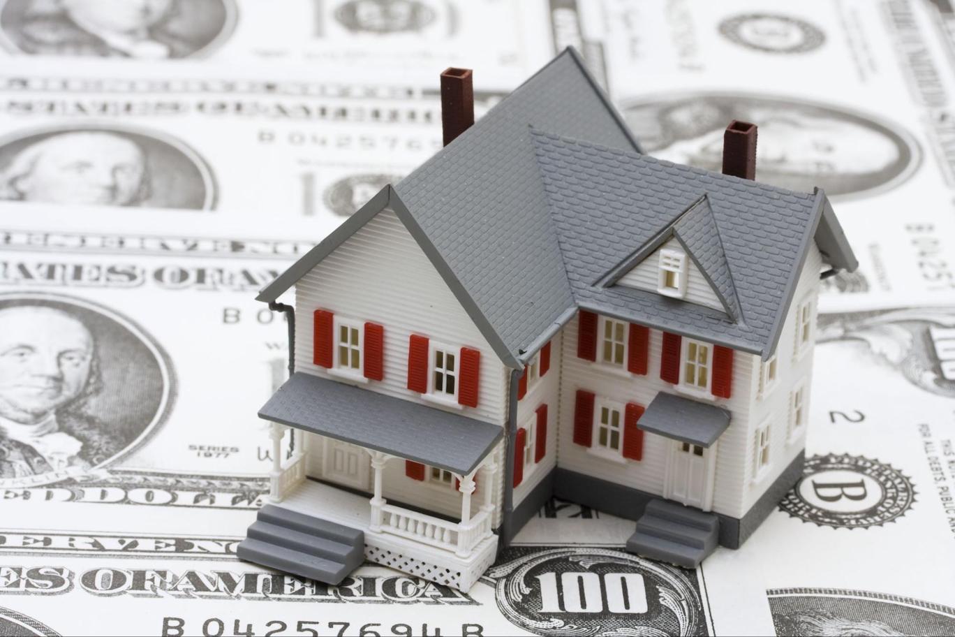 Model house sitting on top of $100 bills
