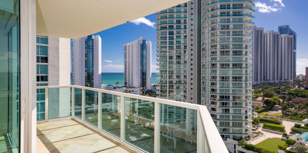 A view of buildings near the water on a sunny day as seen from the balcony of a condo. 