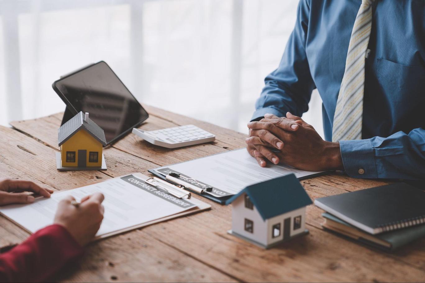 Close up of a prospective home buyer and mortgage professional signing an agreement