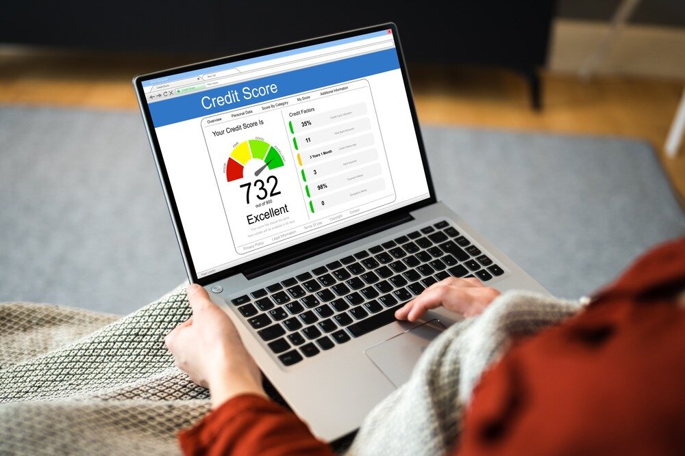 Close-up of a person sitting on the couch with a blanket on while checking their credit report.