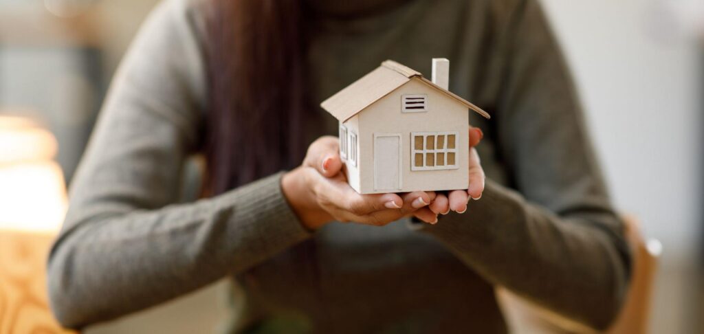 A woman holding up a model home.