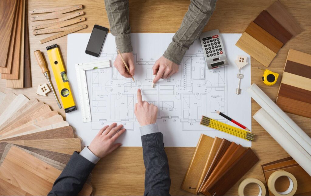 Two people review renovation blueprints and wood samples.