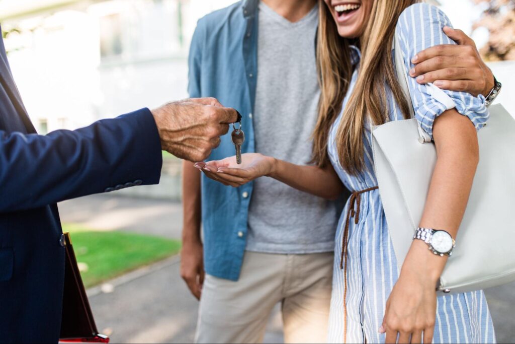 A realtor handing over the house keys to a young couple.