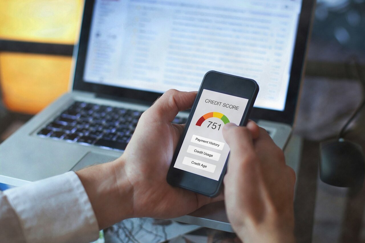 Close up of woman’s hands holding a cell phone looking up her credit score of 751.