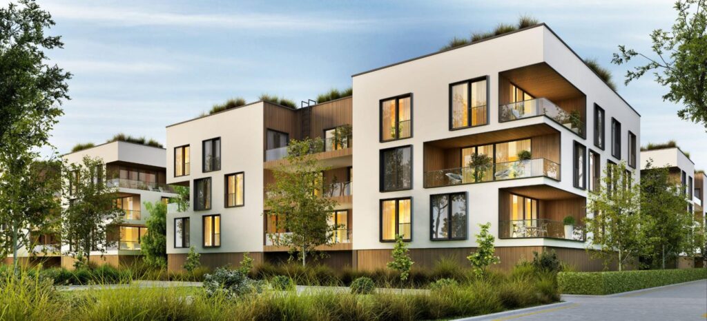 A white modern condo building surrounded by green trees and shrubs.