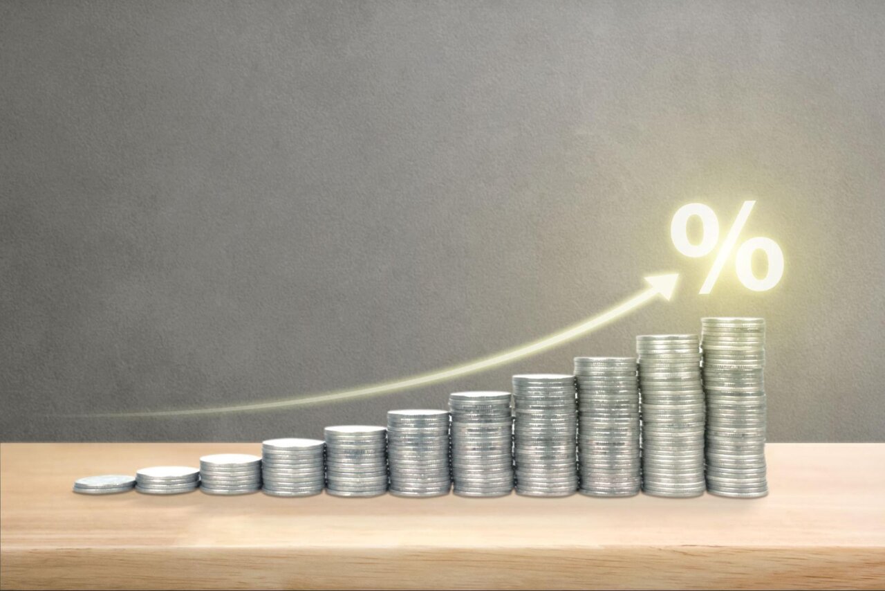 Stacks of coins in ascending order with an arrow and percent symbol trending up