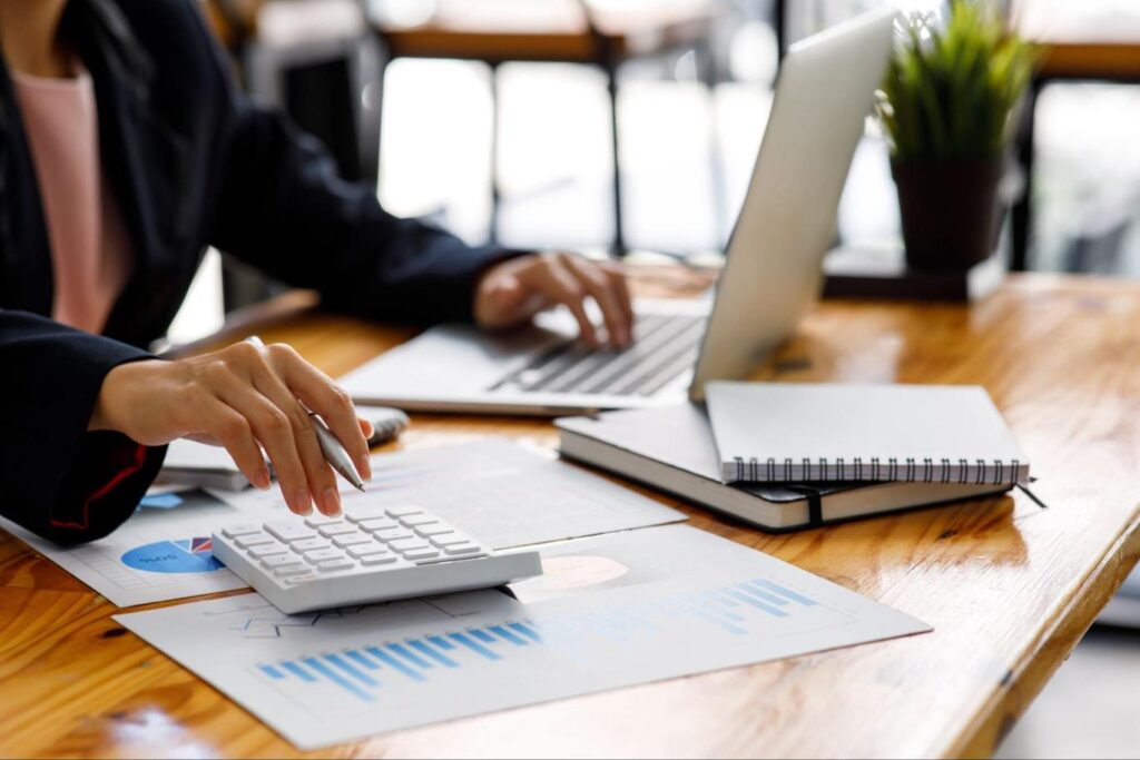 Image of a businesswoman calculating and using her laptop.