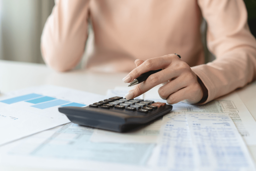 A woman using a calculator while reviewing financial documents.