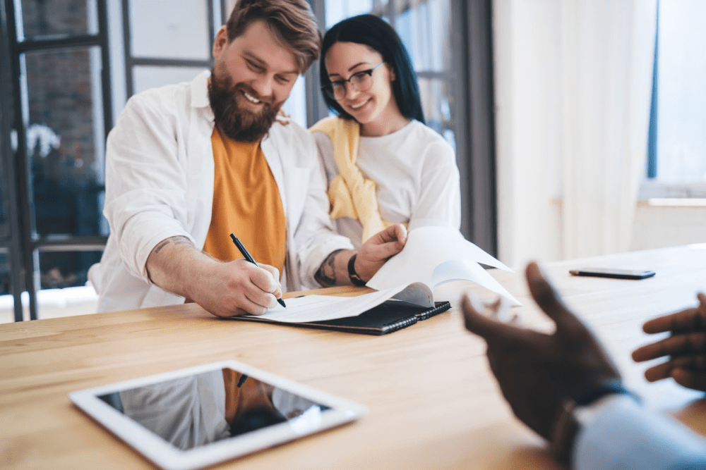 A young happy couple signs a mortgage document.