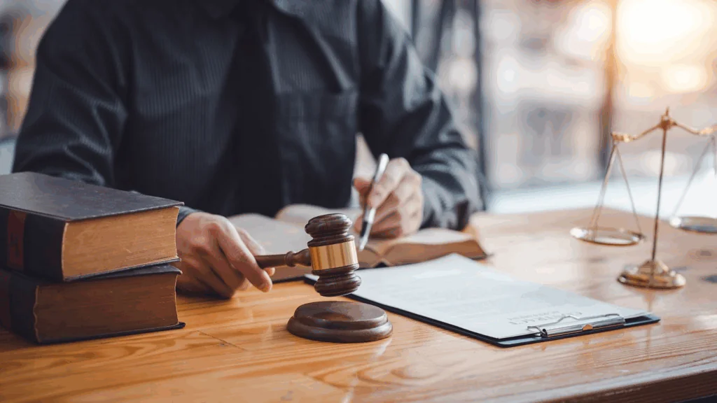 A judge holding a gavel and reviewing documents at his desk.