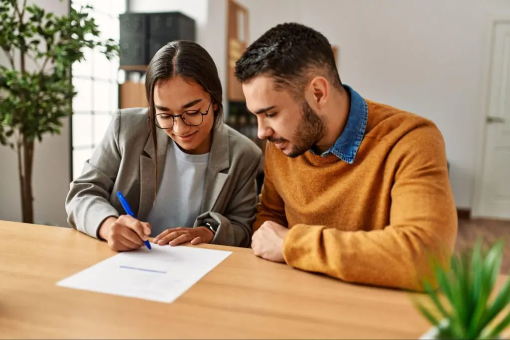 A young couple signs a mortgage document.