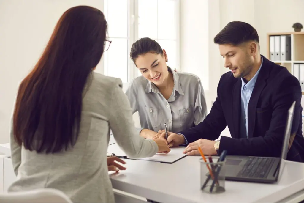 A couple signing documents with a mortgage professional.