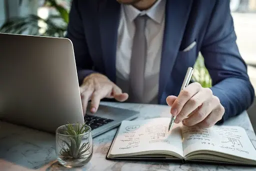 Alt: A businessman creating a business plan in a notebook.